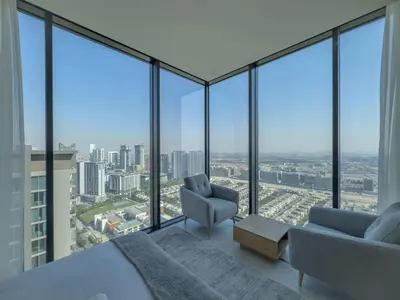 a bedroom with a bed and a chair and windows at Elegant 2-BR with modern comfort in Dubai