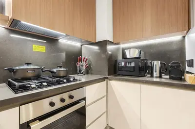 a kitchen with a stove with pots and pans at Luxury 1BR in Business Bay with Burj Khalifa Views, Balcony, Pool and Gym Access in Dubai