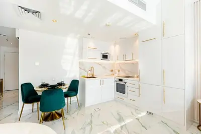 a kitchen with white cabinets and a table and chairs at Chic City Retreat Steps from Dubai Mall & Dubai Opera in Dubai
