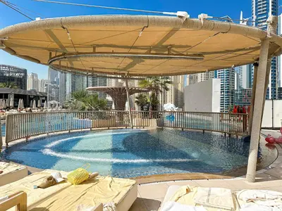 a large swimming pool with a large umbrella at Cinematic View Studio - Emaar Residences in Dubai
