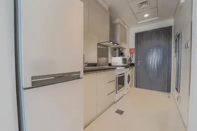 a kitchen with white cabinets and a door to a room at Studio in Damac H1 by Deleguest in Dubai