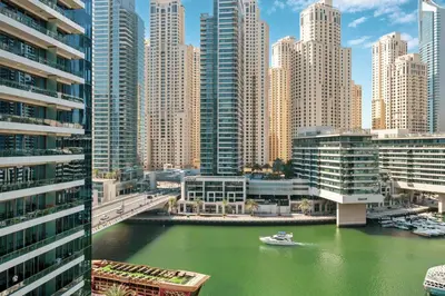 a boat in a river in a city with tall buildings at Luxury Studio in Dubai Marina with Canal views in Dubai