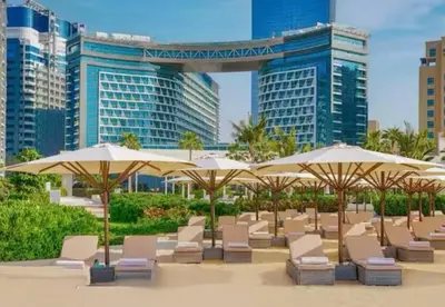 a row of chairs and umbrellas in front of buildings at High-floor 1 Bedroom by Seven Apartments Palm Jumeirah in Dubai