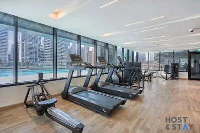 a gym with a row of treadmills and exercise bikes at Cozy Studio in Binghatti Canal - Close to Downtown in Dubai