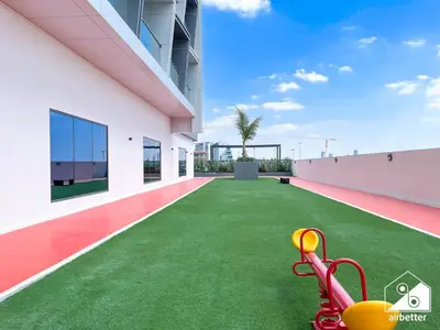a large white building with a green yard with a playground at Serene Studio with Views in Al Waleed Garden 2 in Dubai