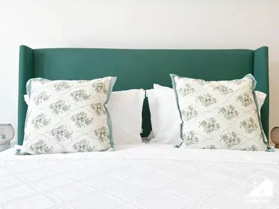 a bed with white pillows and a green headboard at Serene Studio with Views in Al Waleed Garden 2 in Dubai