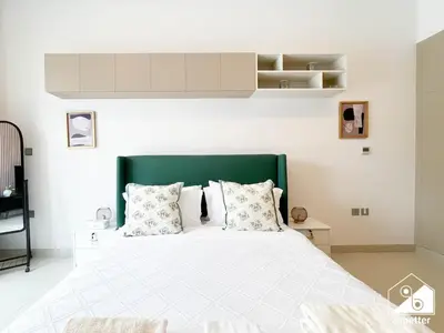 a bedroom with a large bed with a green headboard at Serene Studio with Views in Al Waleed Garden 2 in Dubai