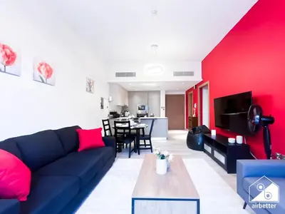 a living room with a blue couch and a red wall at Chic Comfort at oxford Residence in Dubai