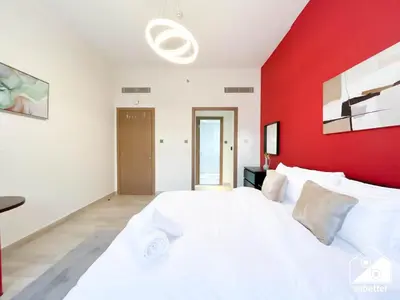 a bedroom with a white bed with a red wall at Chic Comfort at oxford Residence in Dubai