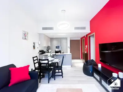 a living room with a table and a red wall at Chic Comfort at oxford Residence in Dubai