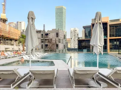 a pool with chairs and umbrellas in a city at Luxe 2BR Retreat, Canal Views & Prime Dubai Stay Near Attractions in Dubai