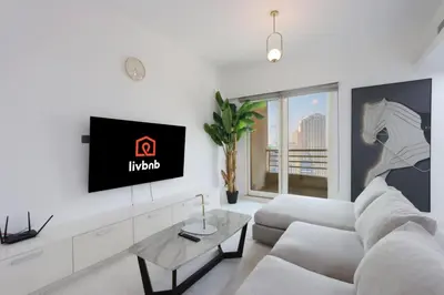 a living room with a white couch and a tv at Livbnb-Upgraded 3B with Marina View,Near Promenade in Dubai
