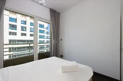 a bedroom with a white bed and a large window at Livbnb-Upgraded 3B with Marina View,Near Promenade in Dubai