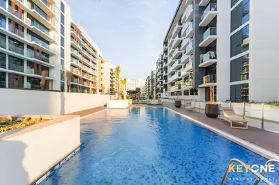 a swimming pool in the middle of two apartment buildings at Chic Modern Studio in Azizi Riviera in Dubai