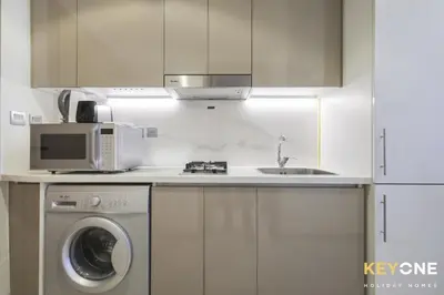 a kitchen with a washing machine and a microwave at Chic Modern Studio in Azizi Riviera in Dubai