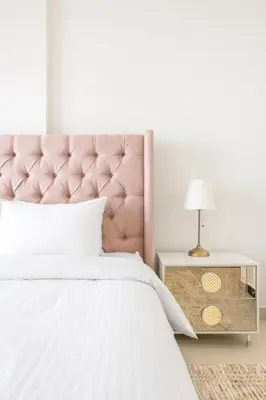 a bed with a pink headboard and a table with a lamp at Fresh & Stylish 2br Living At Collective Tower 1 in Dubai