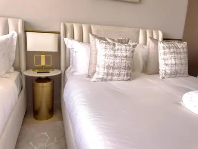 a bed with white sheets and pillows and a lamp at GRANDE SIGNATURE with a direct Burj Khalifa view and Private Fountain Show with DXB AIRPORT VIP Shuttle option for 8 guests in Dubai