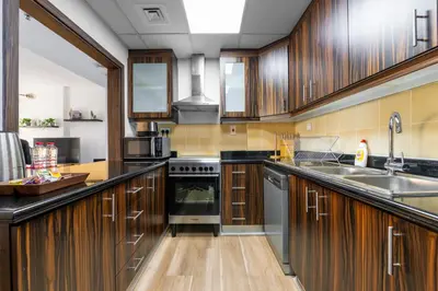a kitchen with wooden cabinets and stainless steel appliances at Luxe Marina View Retreat! 2BDRM in Dubai