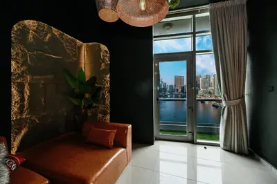 a living room with a chair and a large window at Black & Bold - Aesthetic Stay in Dubai
