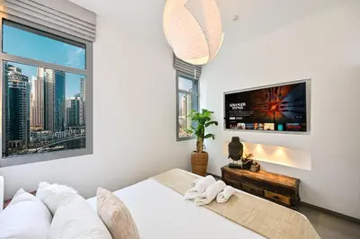 a white bedroom with a white couch and a tv at Black & Bold - Aesthetic Stay in Dubai