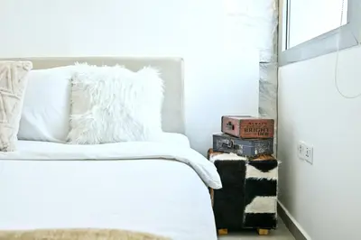 a bedroom with a bed with white sheets and a window at Black & Bold - Aesthetic Stay in Dubai