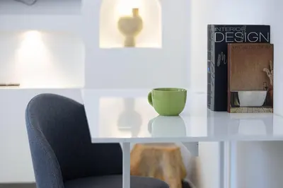 a table with a green cup and a book and a chair at Black & Bold - Aesthetic Stay in Dubai
