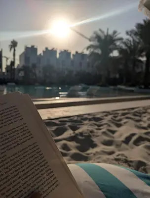 a book sitting on a beach with a view of a city at Stylish Urban-Jungle-Studio in Al Barari, Dubai in Dubai