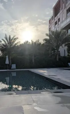 a swimming pool in front of a building with palm trees at Stylish Urban-Jungle-Studio in Al Barari, Dubai in Dubai