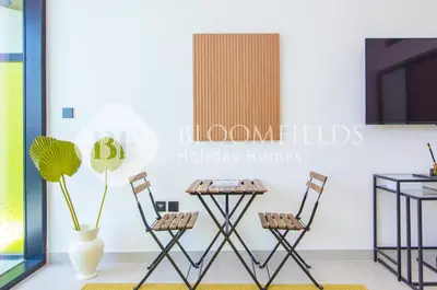 a room with two chairs and a table and a plant at Bloomfields Amber Horizon Stu Binghatti in Dubai