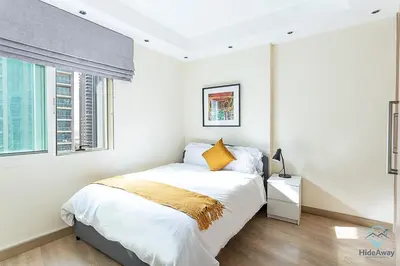 a white bedroom with a bed and two windows at 2BR Breathtaking Waterfront Heart of Marina in Dubai