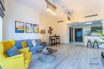 a living room with a blue couch and a table at 1BR Modern, Stylish l Mins to Beach l Dubai Marina in Dubai