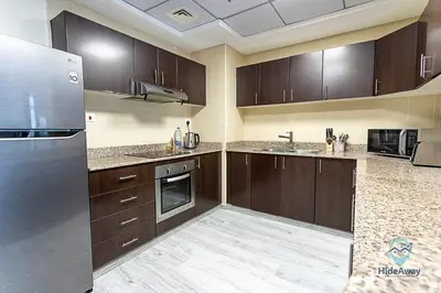 a kitchen with wooden cabinets and a stainless steel refrigerator at 1BR Modern, Stylish l Mins to Beach l Dubai Marina in Dubai