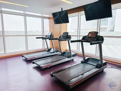 a row of treadmills in a gym with windows at Luxurious Studio in Damac Hills in Dubai