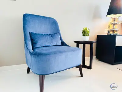 a blue chair in a room with a side table at Luxurious Studio in Damac Hills in Dubai