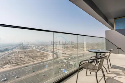 a balcony with a table and chairs looking out at a highway at Skyline-View 1BR with Balcony,Minutes to Downtown and Marina, Binghatti Onyx, Jumeirah Village Circle by Deluxe Holiday Homes in Dubai
