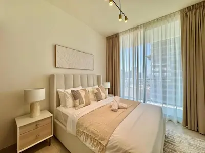 a bedroom with a bed and a large window at Chic Jvc 1br Pool Access, Balcony & Parking in Dubai