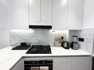 a kitchen with white cabinets and a stove top oven at Chic Jvc 1br Pool Access, Balcony & Parking in Dubai