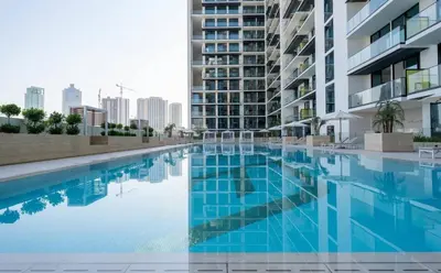 a swimming pool in front of a building at Chic Jvc 1br Pool Access, Balcony & Parking in Dubai
