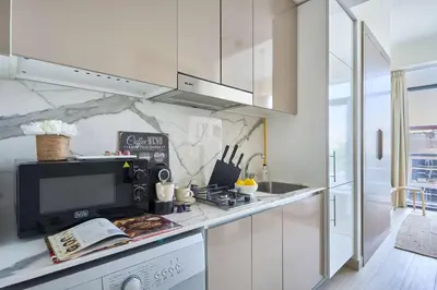 a kitchen with white cabinets and a sink and a microwave at Frank Porter - Azizi Riviera 16 in Dubai