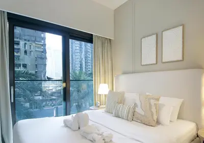 a white bedroom with a bed and a large window at Modern 1BR in Downtown Near Burj Khalifa & Metro in Dubai