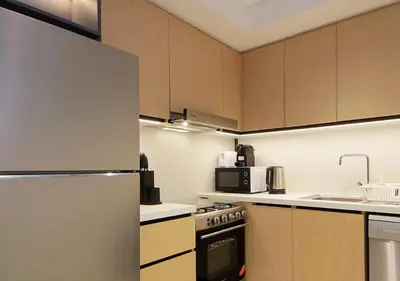 a kitchen with wooden cabinets and a refrigerator at Modern 1BR in Downtown Near Burj Khalifa & Metro in Dubai