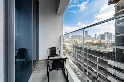 a balcony with two chairs and a view of a city at Elegant 1BDR apartment in JVC in Dubai