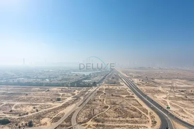 an aerial view of the desert with the deluce sign in the background at High-Rise 1BR with Lake and City Views Easy Access to Downtown and Marina, Binghatti Onyx, Jumeirah Village Circle by Deluxe Holiday Homes in Dubai