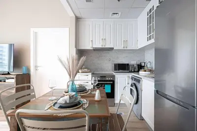 a kitchen with a wooden table and white cabinets at 1BR Beach House Vibes in Prime Marina Location in Dubai