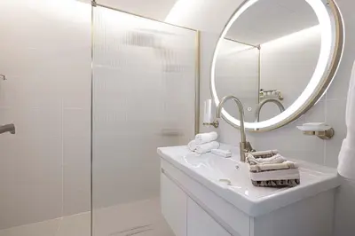a white bathroom with a sink and a mirror at 1BR Beach House Vibes in Prime Marina Location in Dubai