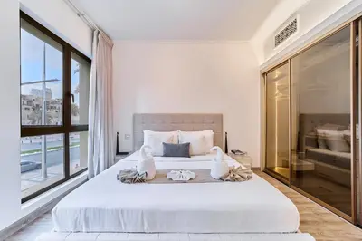 a bedroom with a large white bed with a window at Luxury 1BR in Zaafran With Stunning Burj Khalifa View in Dubai