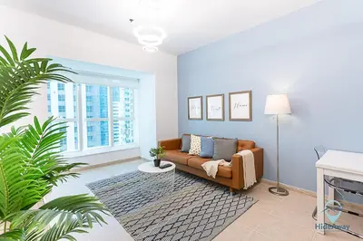 a living room with a couch and a large window at 1BR Tropical Vibes Near Skydiving and Beach! in Dubai