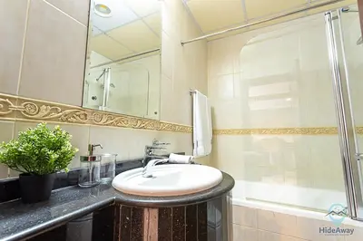 a bathroom with a sink and a mirror and a tub at 1BR Tropical Vibes Near Skydiving and Beach! in Dubai
