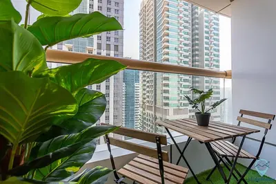 a balcony with a wooden table and chairs and plants at 1BR Tropical Vibes Near Skydiving and Beach! in Dubai