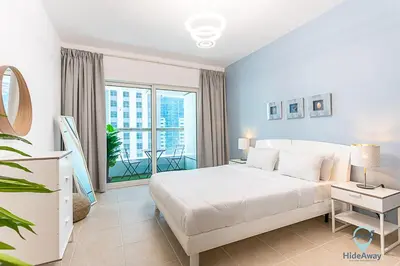 a bedroom with a white bed and a balcony at 1BR Tropical Vibes Near Skydiving and Beach! in Dubai